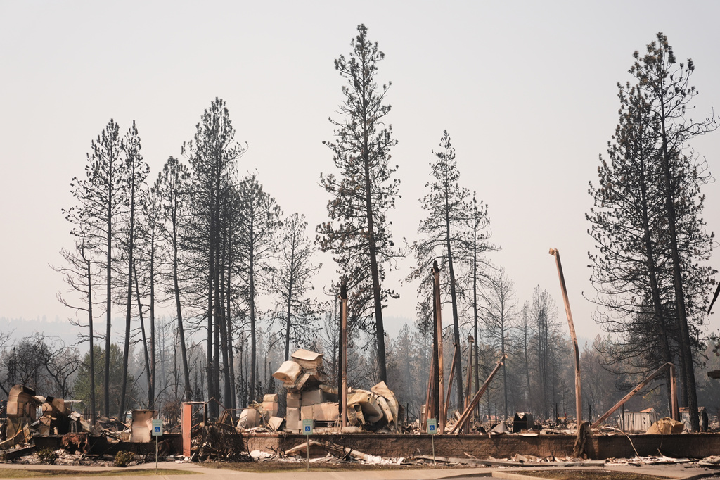 Scorched trees stand over the remains of Riverside Real Life church Tuesday, Aug. 4, 2026, after a wildfire hit the northern part of Spokane, Wash. (AP Photo/Lindsey Wasson)