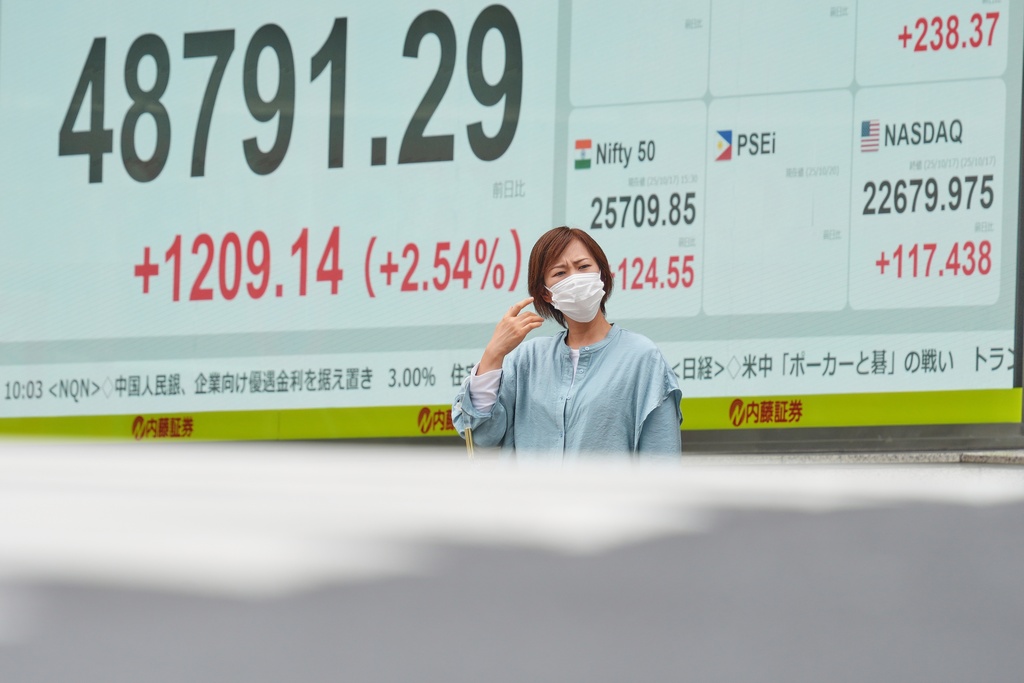 A person stands in front of an electronic stock board showing Japan's Nikkei index at a securities firm Monday, Oct. 20, 2025, in Tokyo. (AP Photo/Eugene Hoshiko)