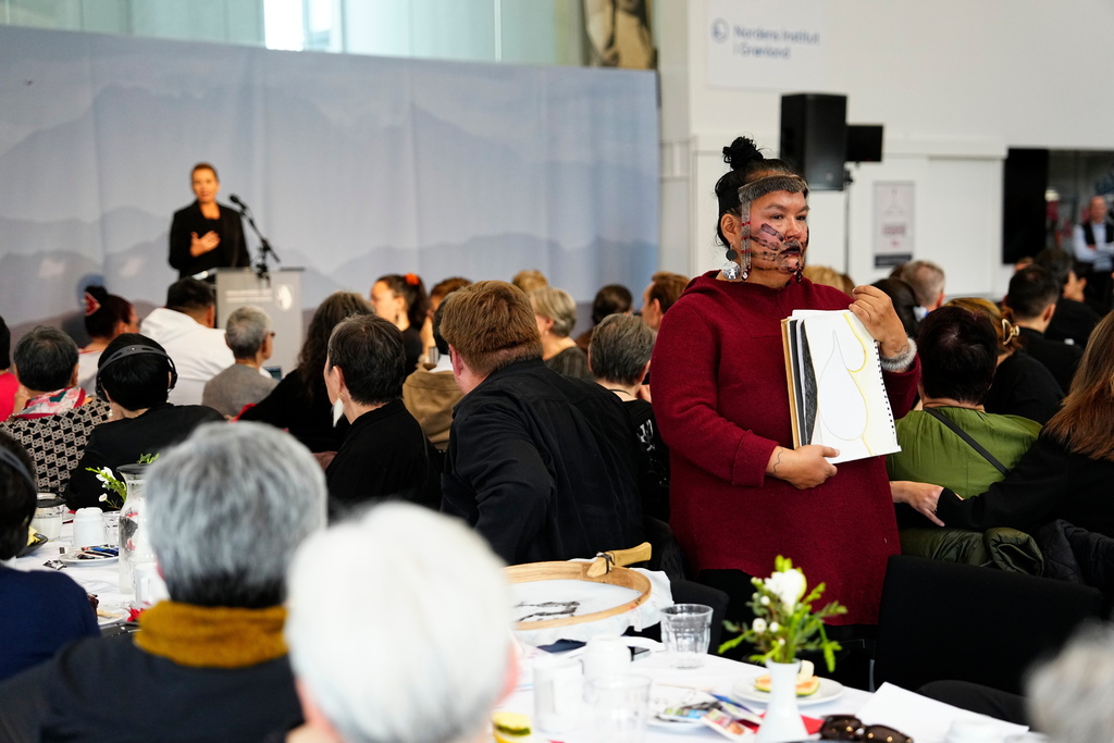 An inuit woman stands with her back to Denmark's Prime Minister Mette Frederiksen as she talks during a meeting in the cultural house Katuaq in Nuuk, Greenland, Wednesday Sept. 24, 2025. (Mads Claus Rasmussen/Ritzau Scanpix via AP)