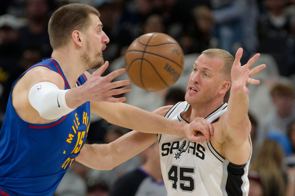 Denver Nuggets center Nikola Jokic (15) passes as he is guarded by San Antonio Spurs center Mason Plumlee during the first half of an NBA basketball game, Sunday, April 12, 2026, in San Antonio. (AP Photo/Darren Abate)