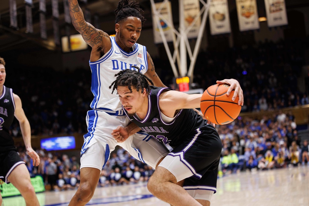 Niagara's Josiah Sabino, right, drives as Duke's Isaiah Evans, center left, defends during the first half of an NCAA college basketball game in Durham, N.C., Friday, Nov. 21, 2025. (AP Photo/Ben McKeown)