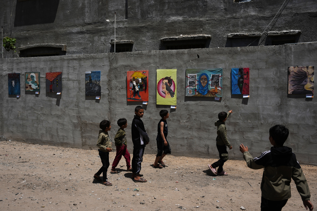 Children look at paintings by Palestinian artists during an exhibition in Al-Bureij camp in the central Gaza Strip Tuesday, April 28, 2026. (AP Photo/Abdel Kareem Hana)