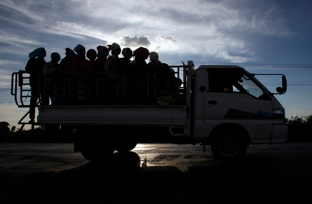FILE -In this Dec. 3, 2018 photo, garment factory workers ride a truck as they go home after a day's work at outside Phnom Penh, Cambodia. (AP Photo/Heng Sinith, File)