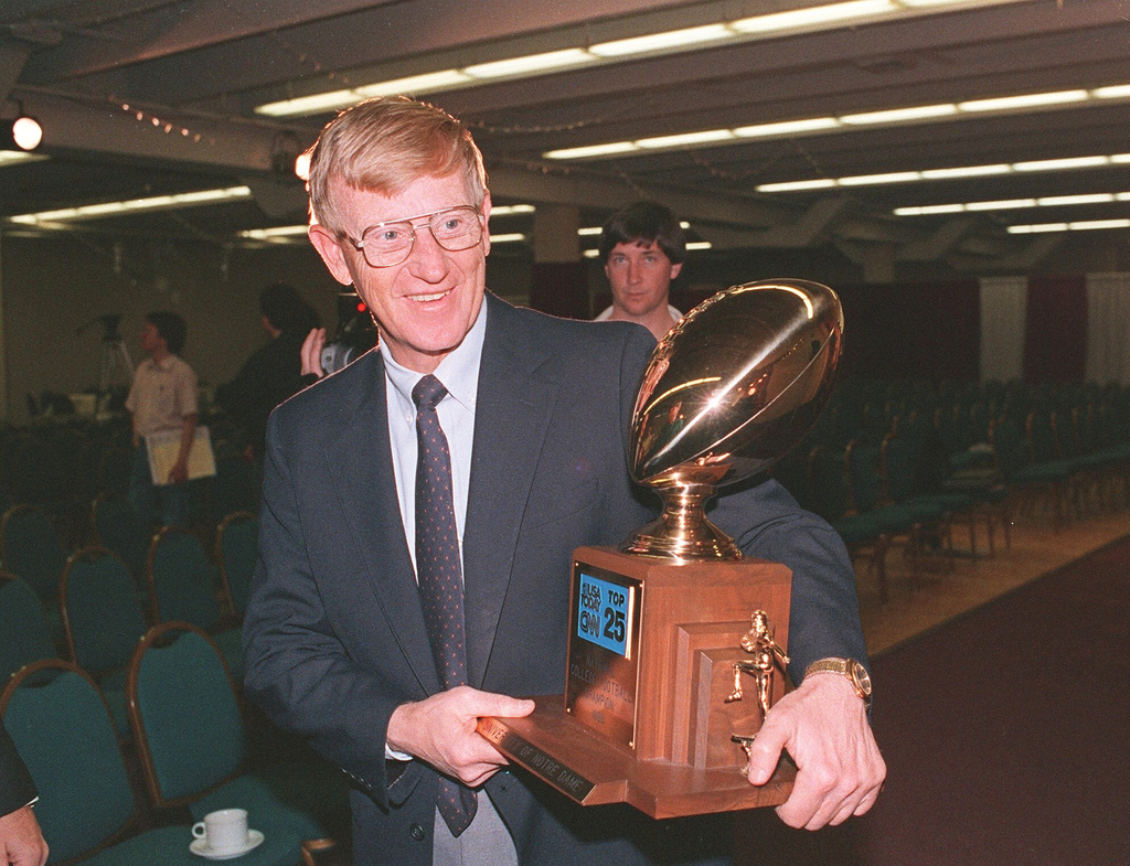 FILE - Notre Dame head coach Lou Holtz carries away the National College Champion Trophy following a news conference in Tempe, Ariz. in this Jan. 3, 1989 photo. (AP Photo/Rob Schmacher, File)