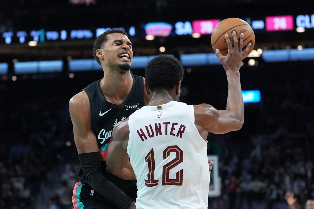 San Antonio Spurs forward Victor Wembanyama, left, crashes into Cleveland Cavaliers forward De'Andre Hunter (12) as they chase a loose ball during the second half of an NBA basketball game in San Antonio, Monday, Dec. 29, 2025. (AP Photo/Eric Gay)