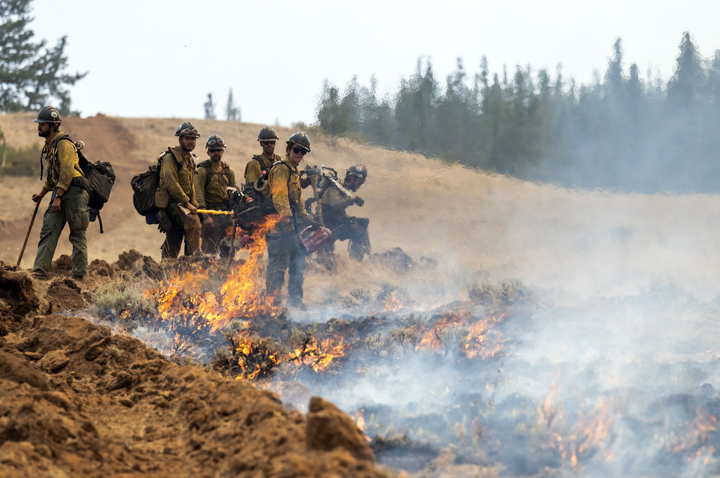 FILE - A wildland fire crew looks on after setting a fire line on Harlow Ridge above the Lick Creek Fire, July 12, 2021, south of Asotin, Wash. (Pete Caster/Lewiston Tribune via AP, File)