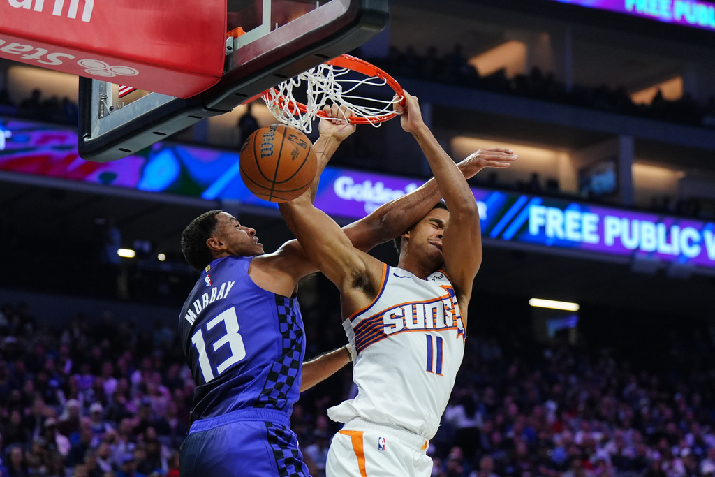 Phoenix Suns forward Oso Ighodaro (11) makes a sum dunk over Sacramento Kings forward Keegan Murray (13) during the first half of an Emirates NBA Cup basketball game Wednesday, Nov. 26, 2025, in Sacramento, Calif. (AP Photo/Alan Greth)