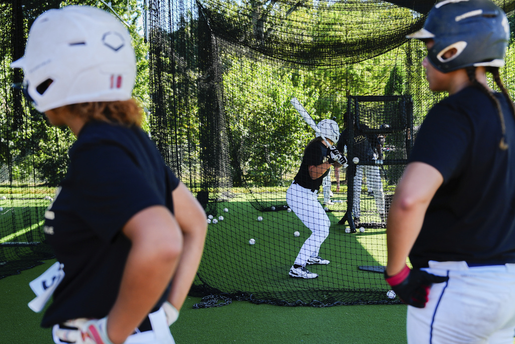 A player hits in a batting cage as others watch during the first day of tryouts for the Women's Professional Baseball League, Friday, Aug 22, 2025, at the Washington Nationals Youth Baseball Academy in Washington. (AP Photo/Julia Demaree Nikhinson)