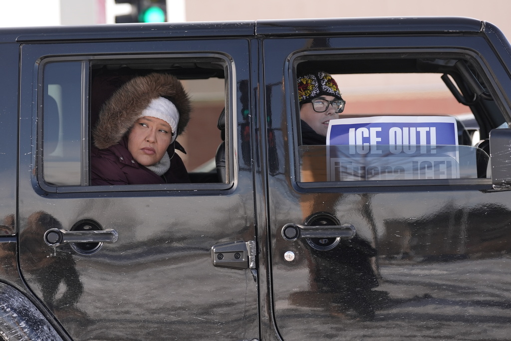 People ride in a car during a caravan protest, Monday, Jan. 19, 2026 in St. Paul, Minn. (AP Photo/Angelina Katsanis)