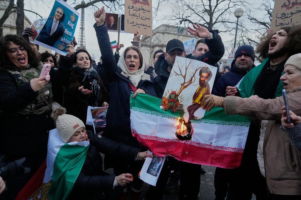 Protesters burn the Iranian national flag during a rally in support of the nationwide mass demonstrations in Iran against the government in Paris, Sunday, Jan. 11, 2026. (AP Photo/Michel Euler)