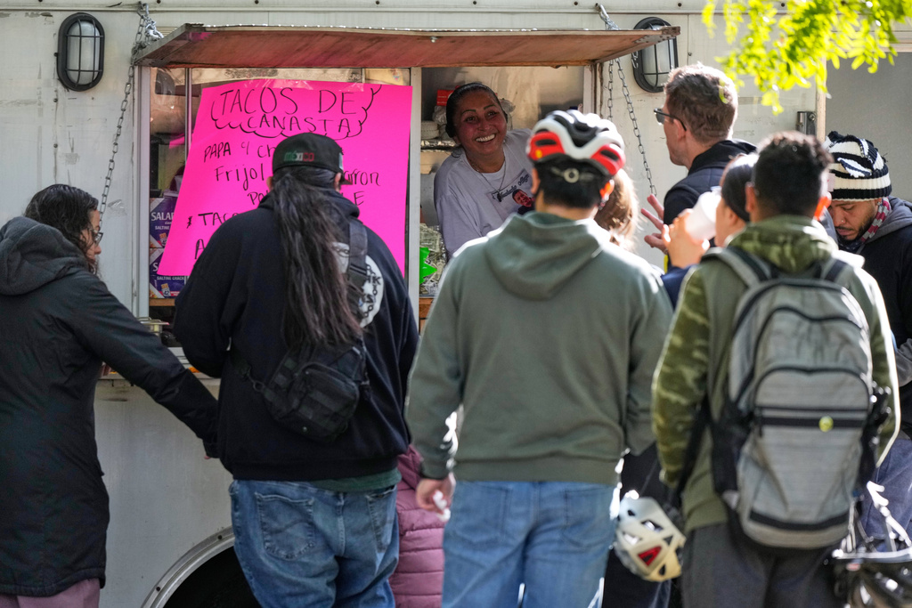 A street vendor Alicia Robles, top, takes orders from people who ride their bicycle at Gage Park during Street Vendor Bike Tour Series, in Chicago, Sunday, Nov. 2, 2025. (AP Photo/Nam Y. Huh)