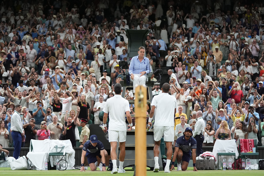 Novak Djokovic of Serbia, left, and Felix Auger-Aliassime of Canada, right, walk towards the empire after greeting each other at the end of their quarter-final men's singles match at the Wimbledon Tennis Championships in London, Tuesday, July 7, 2026. (AP Photo/Maja Smiejkowska)