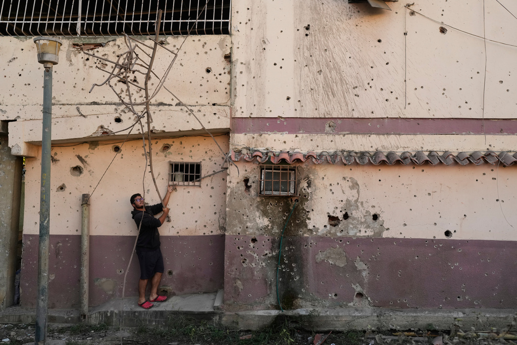 Dressle Perez removes twisted metal from a damaged apartment complex that residents say was hit during U.S. strikes to capture Venezuelan President Nicolás Maduro, in Catia La Mar, Venezuela, Sunday, Jan. 4, 2026.(AP Photo/Matias Delacroix)