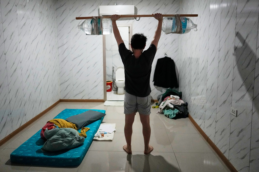 A rescued Vietnamese scam worker shows how he exercises using improvised weights made of a wooden stick and water jugs as he waits to be repatriated at the Presidential Anti-Organized Crime Commission temporary detention center, a former scam compound in Pasay, Philippines, Tuesday, June 3, 2025. (AP Photo/Aaron Favila)