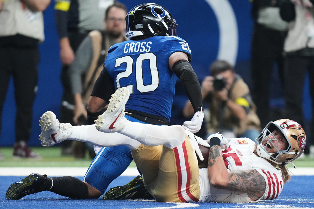San Francisco 49ers tight end George Kittle, bottom, smiles after catching a touchdown pass against Indianapolis Colts safety Nick Cross (20) during the first half of an NFL football game, Monday, Dec. 22, 2025, in Indianapolis. (AP Photo/AJ Mast)