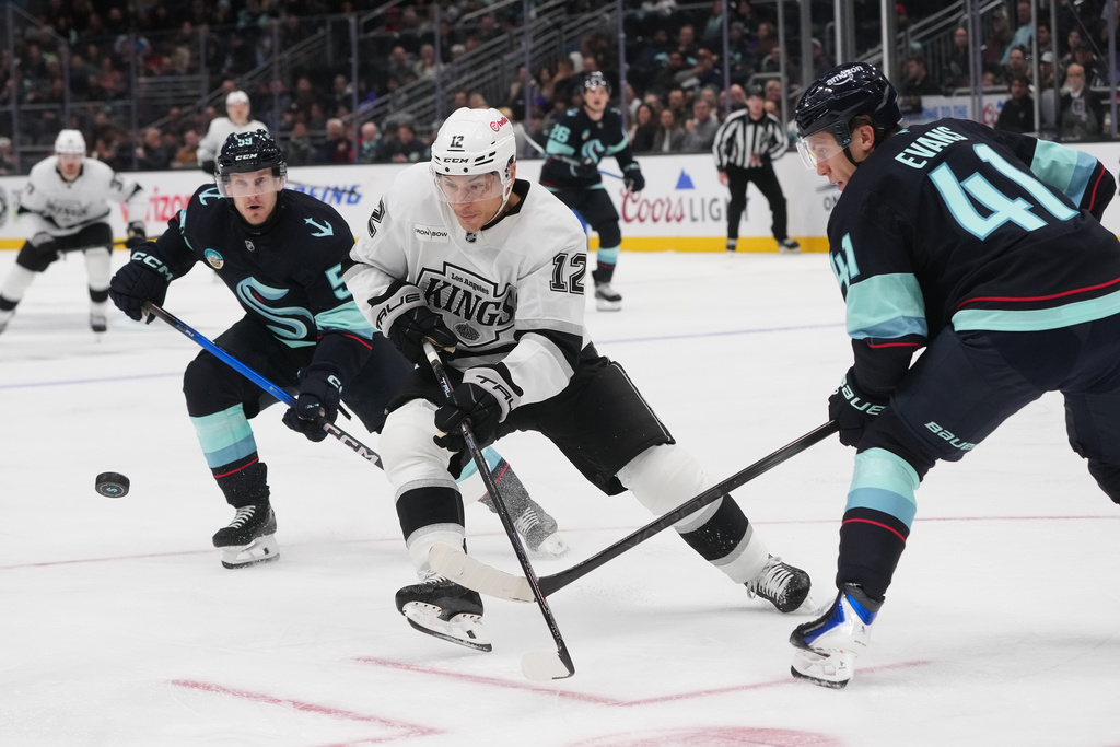 Los Angeles Kings left wing Trevor Moore (12) follows the puck against Seattle Kraken defenseman Ryker Evans (41) during the third period of an NHL hockey game Wednesday, Dec. 10, 2025, in Seattle. (AP Photo/Lindsey Wasson)