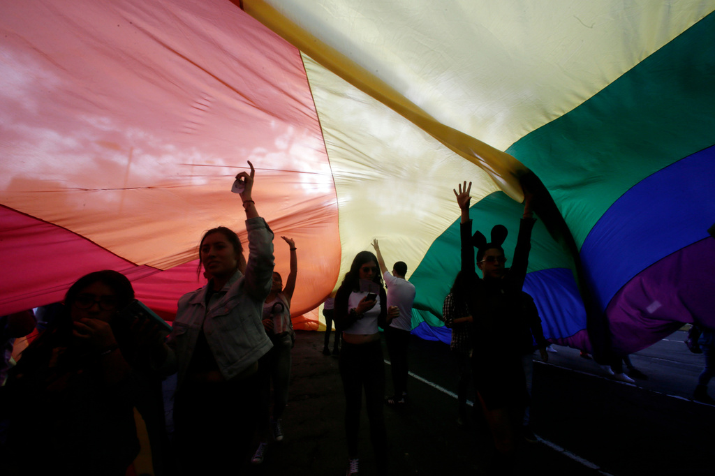 FILE - Revelers walk under a giant rainbow flag during a Pride Parade in Quito, Ecuador, June 29, 2019. (AP Photo/Dolores Ochoa, File)