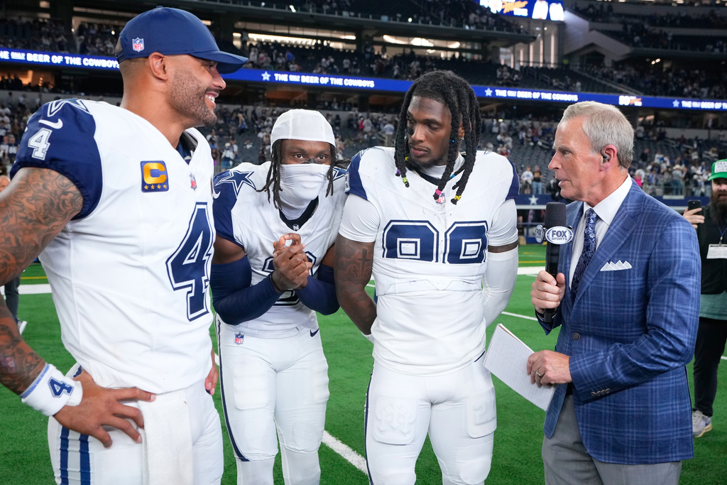 Fox broadcast reporter Tom Rinaldi, right, interviews Dallas Cowboys quarterback Dak Prescott, left, wide receiver George Pickens (3) and wide receiver Ceedee Lamb (88) following an NFL football game against the Washington Commanders Sunday, Oct. 19, 2025, in Arlington, Texas. (AP Photo/Jeffrey McWhorter)