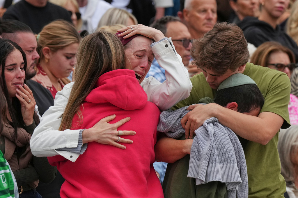 A family reacts during a menorah lighting ceremony at a floral memorial for victims of Sunday's shooting, at the Bondi Pavilion on Bondi Beach on Tuesday, Dec. 16, 2025, in Sydney, Australia. (AP Photo/Mark Baker)