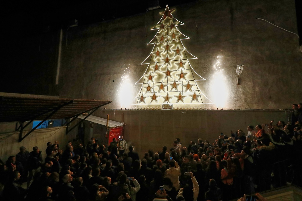 People attend the lighting of a Christmas tree at the Greek Orthodox Mar Elias Church, months after the church was the site of a deadly suicide bombing, in the Dweila neighborhood of Damascus, Syria, Tuesday, Dec. 23, 2025.(AP Photo/Omar Sanadiki)