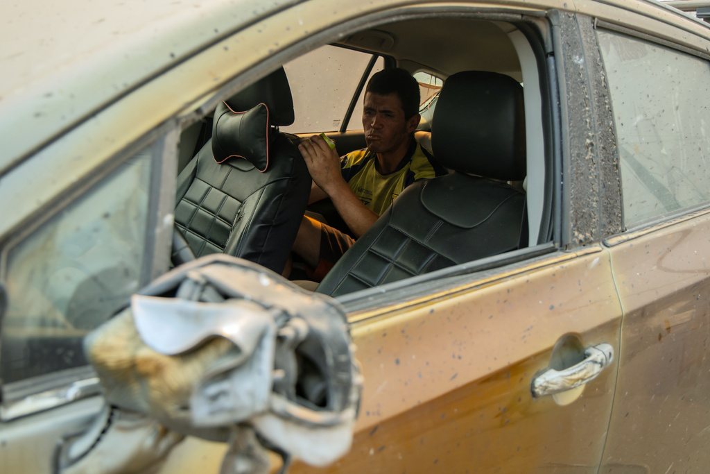 Reimundo Neira sits inside a vehicle, damaged by fire, after his home burned down in Lirquen, Chile, Sunday, Jan. 18, 2026. (AP Photo/Javier Torres)