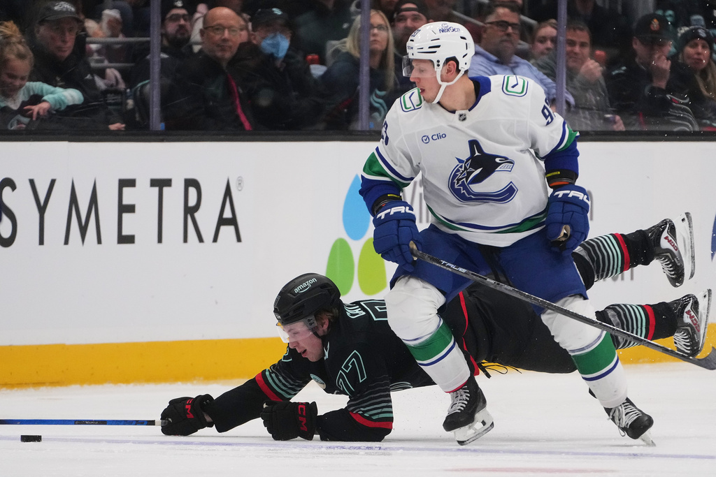 Seattle Kraken center Berkly Catton, left, falls against Vancouver Canucks center Marco Rossi, right, during the third period of an NHL hockey game Monday, Dec. 29, 2025, in Seattle. (AP Photo/Lindsey Wasson)