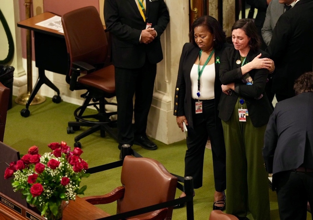 Democratic representatives Rep. Mary Clardy and Rep. Kristi Pursell tearful stand behind the empty desk of former Rep. Melissa Hortman, with flowers on it, as they arrive to the House Chambers on opening day of the Minnesota Legislature at the State Capitol in St Paul, Minn., on Tuesday, Feb. 17, 2026. (Renée Jones Schneider/Star Tribune via AP)