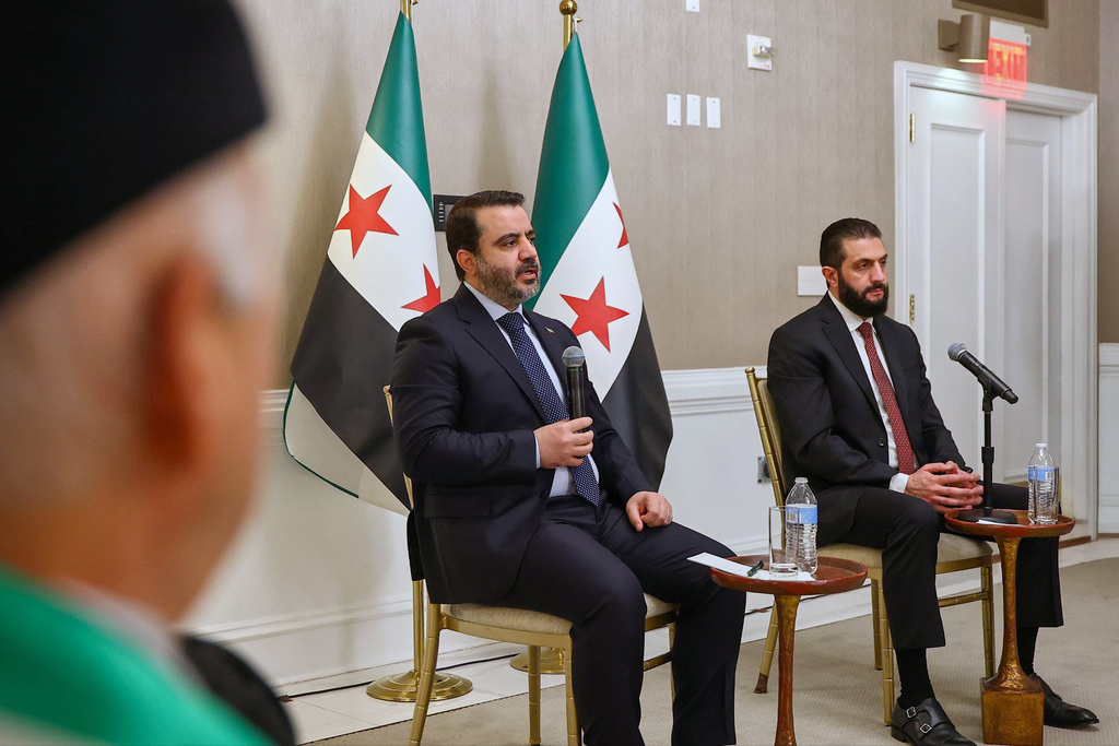 In this photo, released by the Syrian Presidency Press Office, Syrian President Ahmad al-Sharaa, right, listens as Syrian Foreign Minister Asaad al-Shibani, center, speaks during a meeting with representatives of Syrian American organizations in Washington, Saturday, Nov. 8, 2025. (Syrian Presidency Press Office via AP)