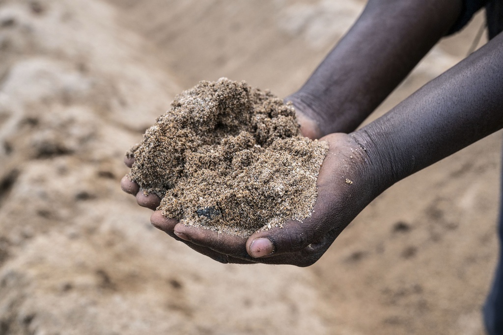 Feluzi Makono holds soil at his grandmother's farm in Mulanje, southern Malawi, Tuesday, July 29, 2025. (AP Photo/Thoko Chikondi)