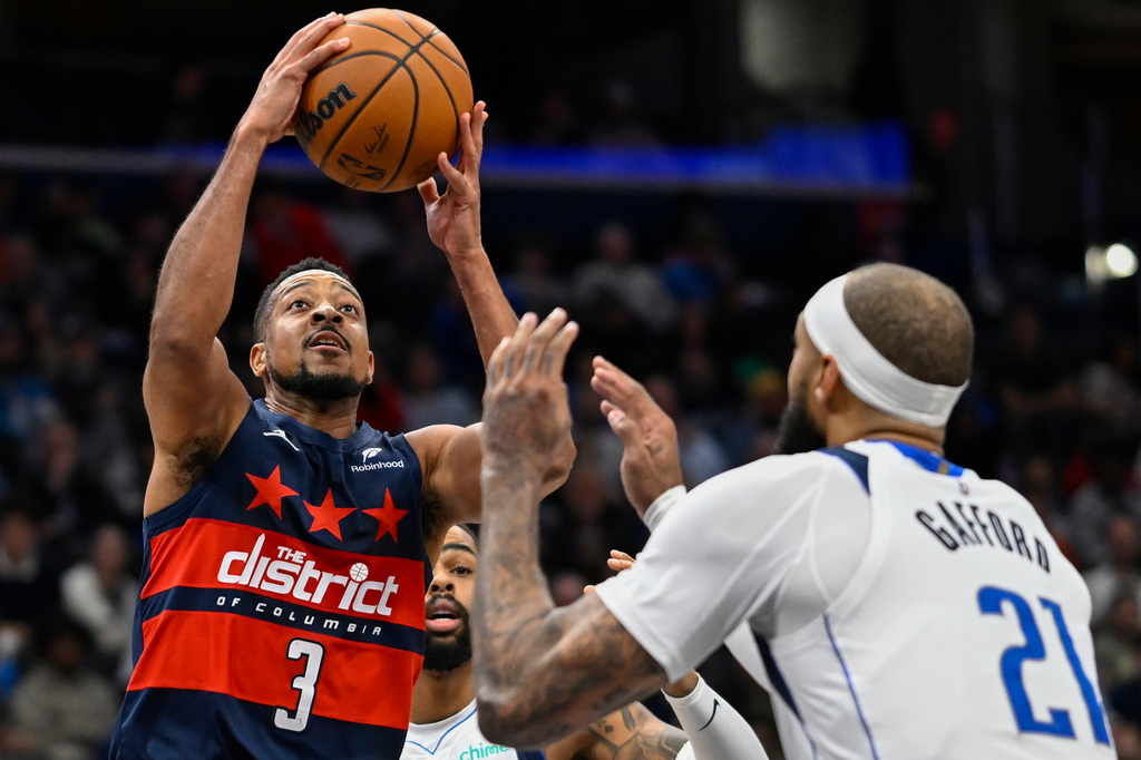 Washington Wizards guard CJ McCollum (3) rises over Dallas Mavericks forward Daniel Gafford (21) for a basket during the first half of an NBA basketball game Saturday, Nov. 8, 2025, in Washington. (AP Photo/John McDonnell)