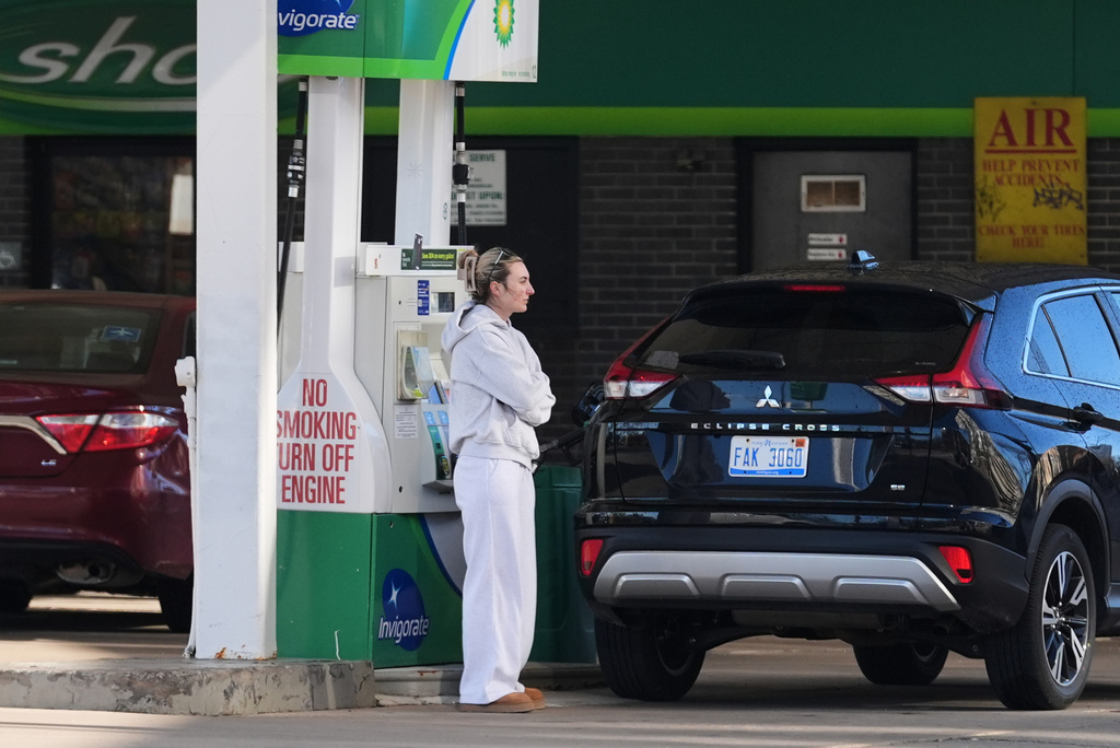 A woman waits as she fills her tank at a gas station in Chicago, Monday, April 6, 2026. (AP Photo/Nam Y. Huh)