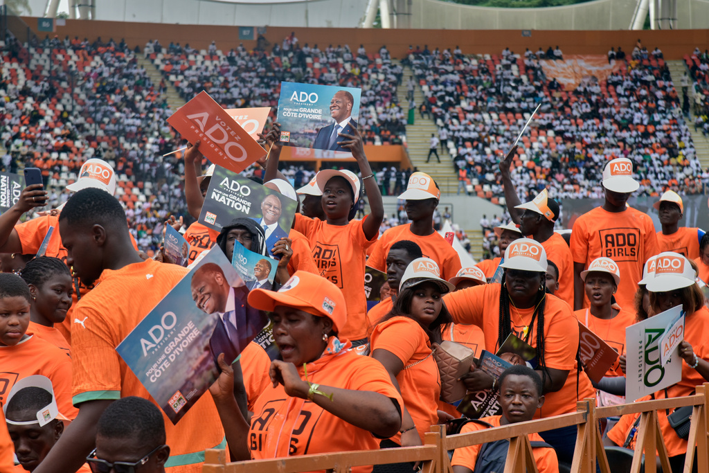 Supporters of President Alassane Ouattara hold posters during a campaign rally at the Félix Houphouët-Boigny Stadium in Abidjan, Ivory Coast, Saturday, Oct. 18, 2025. (AP Photo/Diomande Ble Blonde)