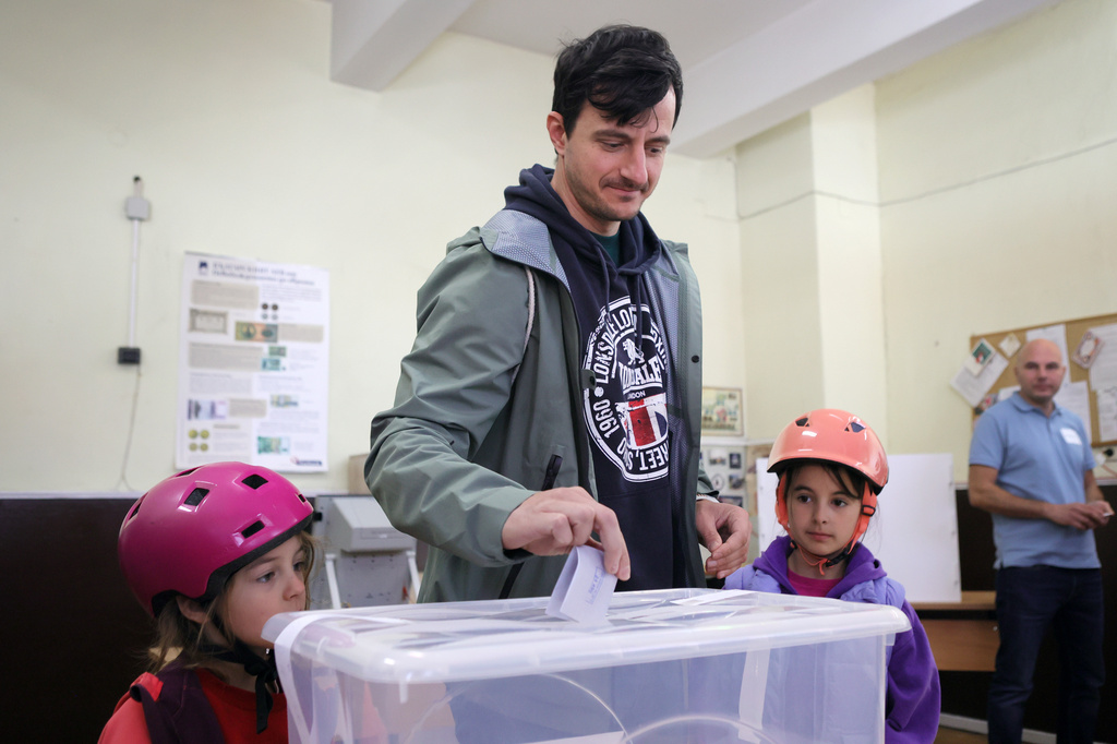 A father casts his ballot, accompanied by his daughters at a polling station in Sofia on Sunday, April 19, 2026, during early parliamentary elections. (AP Photo/Valentina Petrova)
