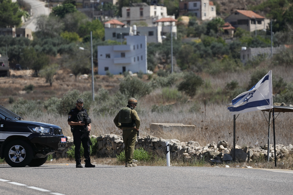 Israeli police officer and a soldier stand guard near the site of a shooting attack that, according to Israeli officials, killed one Israeli near the settlement of Neve Tzuf, north of the West Bank city of Ramallah, Sunday, Sept. 20, 2026. (AP Photo/Mahmoud Illean)