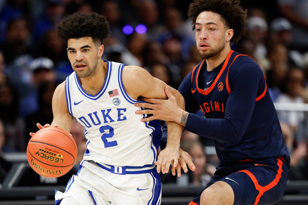 Duke guard Cayden Boozer (2) moves the ball against Virginia guard Sam Lewis during the first half of an NCAA college basketball game in the championship of the Atlantic Coast Conference tournament in Charlotte, N.C., Saturday, March 14, 2026. (AP Photo/Nell Redmond)