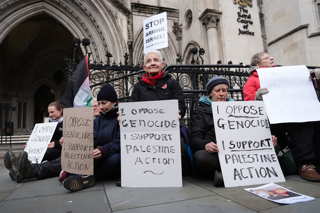 Protesters hold placards outside the High Court, in London, Friday Feb. 13, 2026, where Judges Victoria Sharp, Jonathan Swift and Karen Steyn have ruled in favour of Palestine Action's co-founder Huda Ammori's challenge over the ban of the organisation as a terror group. (Jonathan Brady/PA via AP)