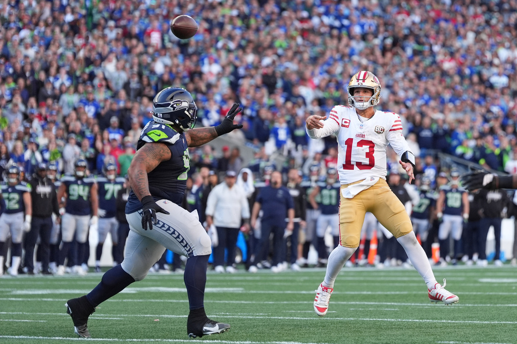 San Francisco 49ers quarterback Brock Purdy (13) throws a 2-point conversion pass as Seattle Seahawks defensive tackle Byron Murphy II (91) tries to apply pressure during the second half of an NFL football game Sunday, Oct. 11, 2026, in Seattle. (AP Photo/Lindsey Wasson)