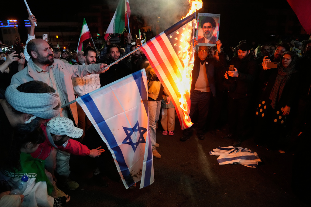 FILE - Iranian pro-government demonstrators burn the U.S. and Israeli flags as one of them holds a picture of the Supreme Leader Ayatollah Mojtaba Khamenei during a gathering after announcement of a two-week ceasefire in the war with the Unites States and Israel at the Enqelab-e-Eslami, or Islamic Revolution, Square in Tehran, Iran, April 8, 2026. (AP Photo/Vahid Salemi, File)