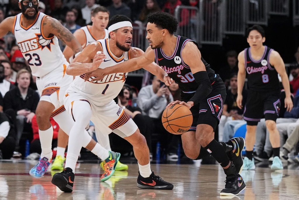Chicago Bulls guard Tre Jones, right, drives against Phoenix Suns guard Devin Booker during the first half of an NBA basketball game in Chicago, Sunday, April 5, 2026. (AP Photo/Nam Y. Huh)