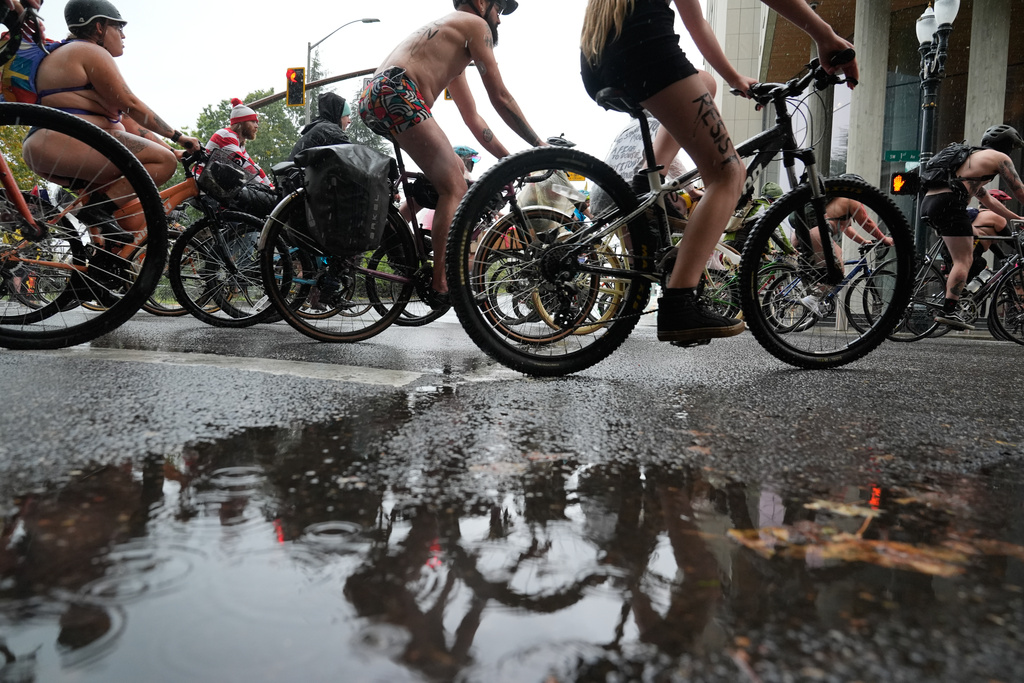 Protesters ride in the rain during the Naked Bike Ride protest on their way to the U.S. Immigration and Customs Enforcement facility on Sunday, Oct. 12, 2025, in Portland, Ore. (AP Photo/Jenny Kane)