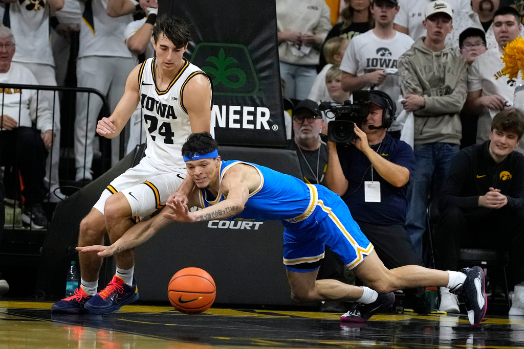 Iowa guard Tate Sage (24) fights for a loose ball with UCLA guard Jamar Brown (4) during the first half of an NCAA college basketball game, Saturday, Jan. 3, 2026, in Iowa City, Iowa. (AP Photo/Charlie Neibergall)