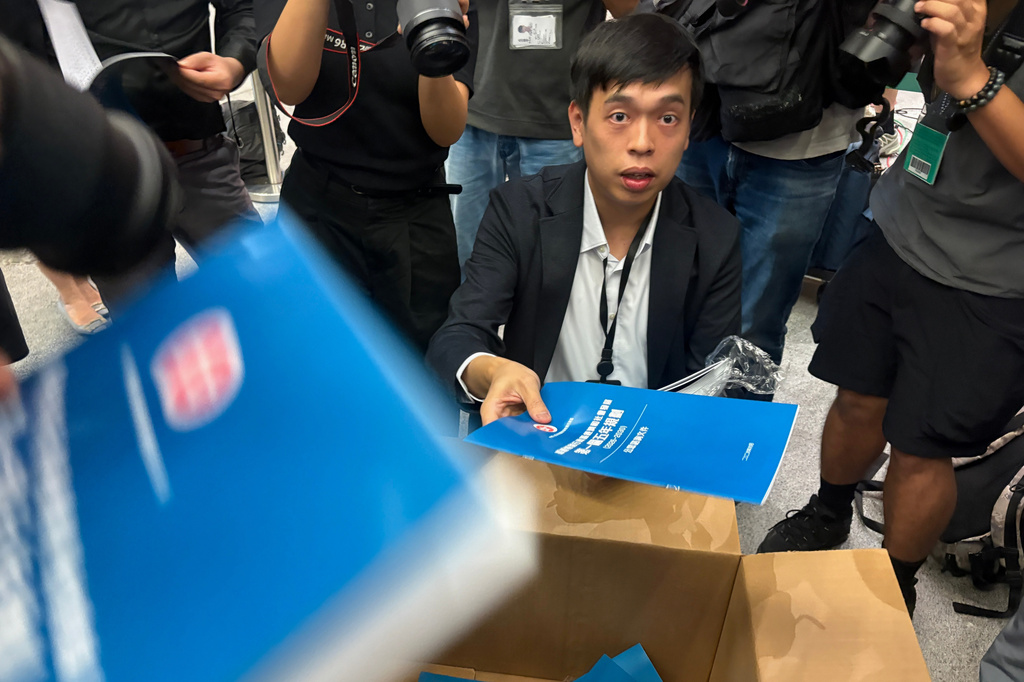 A man gives out copies of public consultation documents for Hong Kong's first five-year plan to reporters at the government headquarters in Admiralty district of Hong Kong, Monday, June 15, 2026. (AP Photo/Kanis Leung)