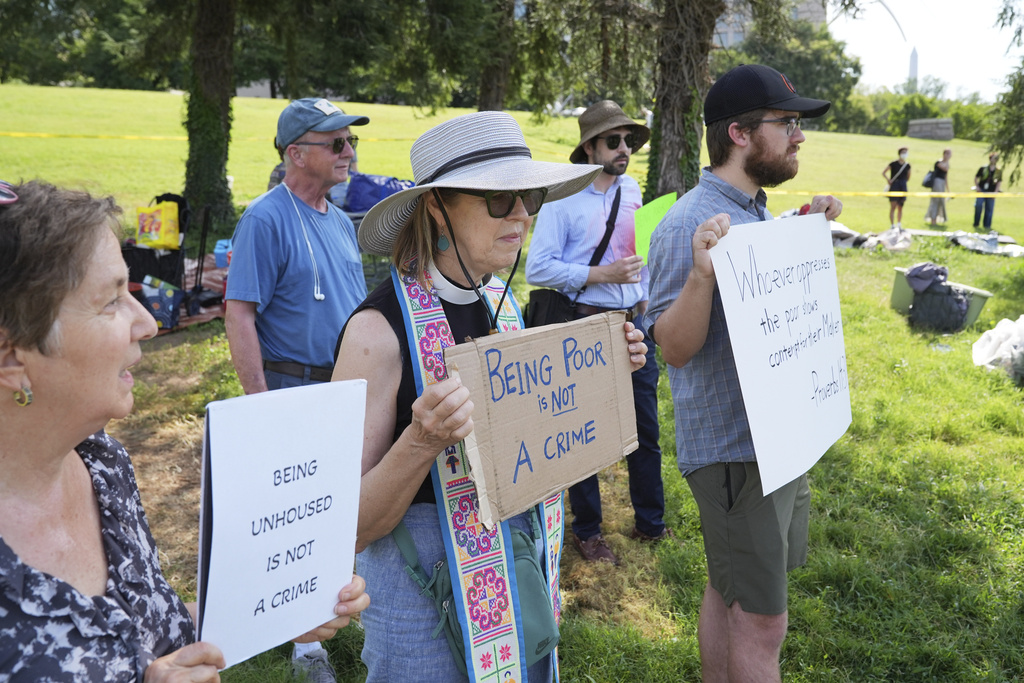 Protesters hold signs at a homeless encampment, Thursday, Aug. 14, 2025 in Washington. (AP Photo/Jacquelyn Martin)
