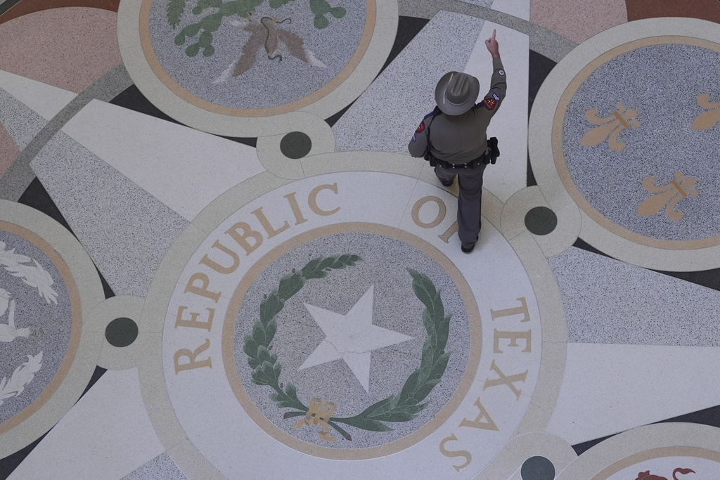A Texas troopers passes the Texas Seal on the Rotunda of the Texas Capitol before debate on a bill for a redrawn U.S. congressional map during a special session in the Senate Chamber in Austin, Texas, Friday, Aug. 22, 2025. (AP Photo/Eric Gay)
