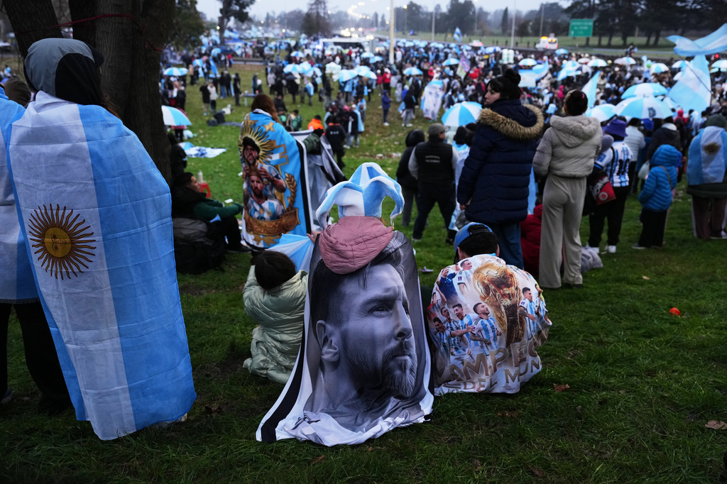 An Argentina fan wrapped in a flag bearing an image of Lionel Messi gathers outside the Argentine Football Association headquarters while waiting for the national team to arrive in Ezeiza, on the outskirts of Buenos Aires, Monday, July 20, 2026, following its World Cup final loss to Spain. (AP Photo/Rodrigo Abd)