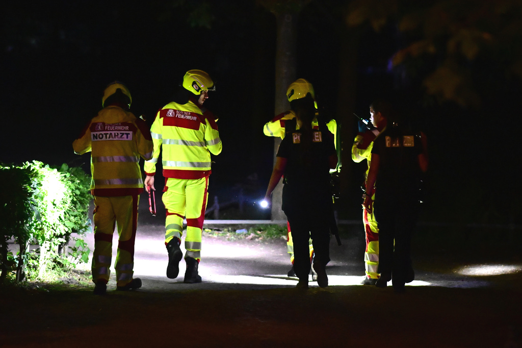 Emergency personnel use flashlights following the cancellation of Christopher Street Day in the Tiergarten area of Berlin on Saturday, July 25, 2026. (Fabian Sommer/dpa via AP)