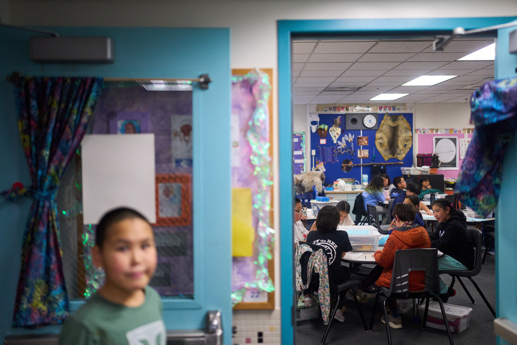 Rayann Martin, a 10-year-old displaced from the village of Kipnuk by ex-Typhoon Halong, front right in black, talks with new classmate Lilly Loewen, 10, in orange, as they work in the Yup'ik language at College Gate Elementary, Thursday, Oct. 30, 2025, in Anchorage, Alaska. (AP Photo/Lindsey Wasson)