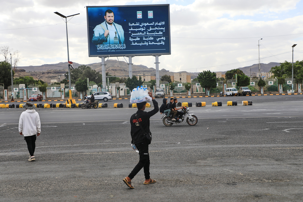 A vendor walks under a billboard showing Houthi leader Abdul Malik al-Houthi with a phrase that reads in Arabic: "The Saudi accusation against our people deserves to be described as the lie of the century" in Sanaa, Yemen, Monday, Oct. 5, 2026. (AP Photo/Osamah Abdulrahman)