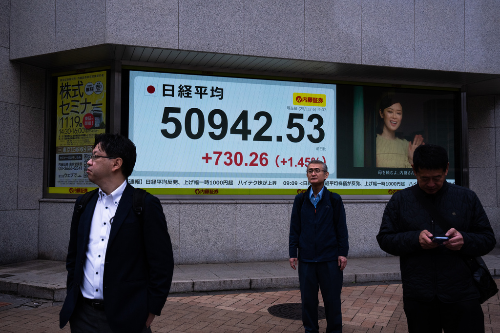 Pedestrians pass an electronic stock board showing Japan's Nikkei index at a securities firm in Tokyo, Thursday, Nov. 6, 2025. (AP Photo/Louise Delmotte)