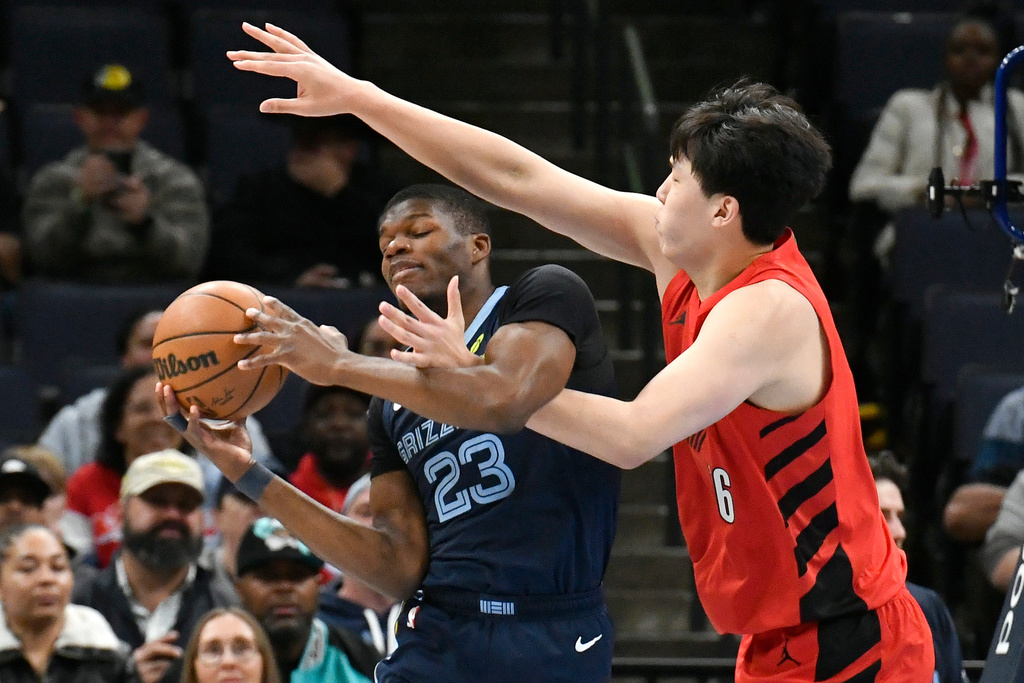 Memphis Grizzlies forward Cedric Coward (23) handles the ball against Portland Trail Blazers center Yang Hansen (16) in the first half of an NBA basketball game Sunday, Dec. 7, 2025, in Memphis, Tenn. (AP Photo/Brandon Dill)